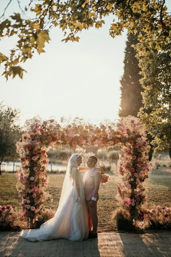 Les mariés sous l’arche fleurie au coucher du soleil