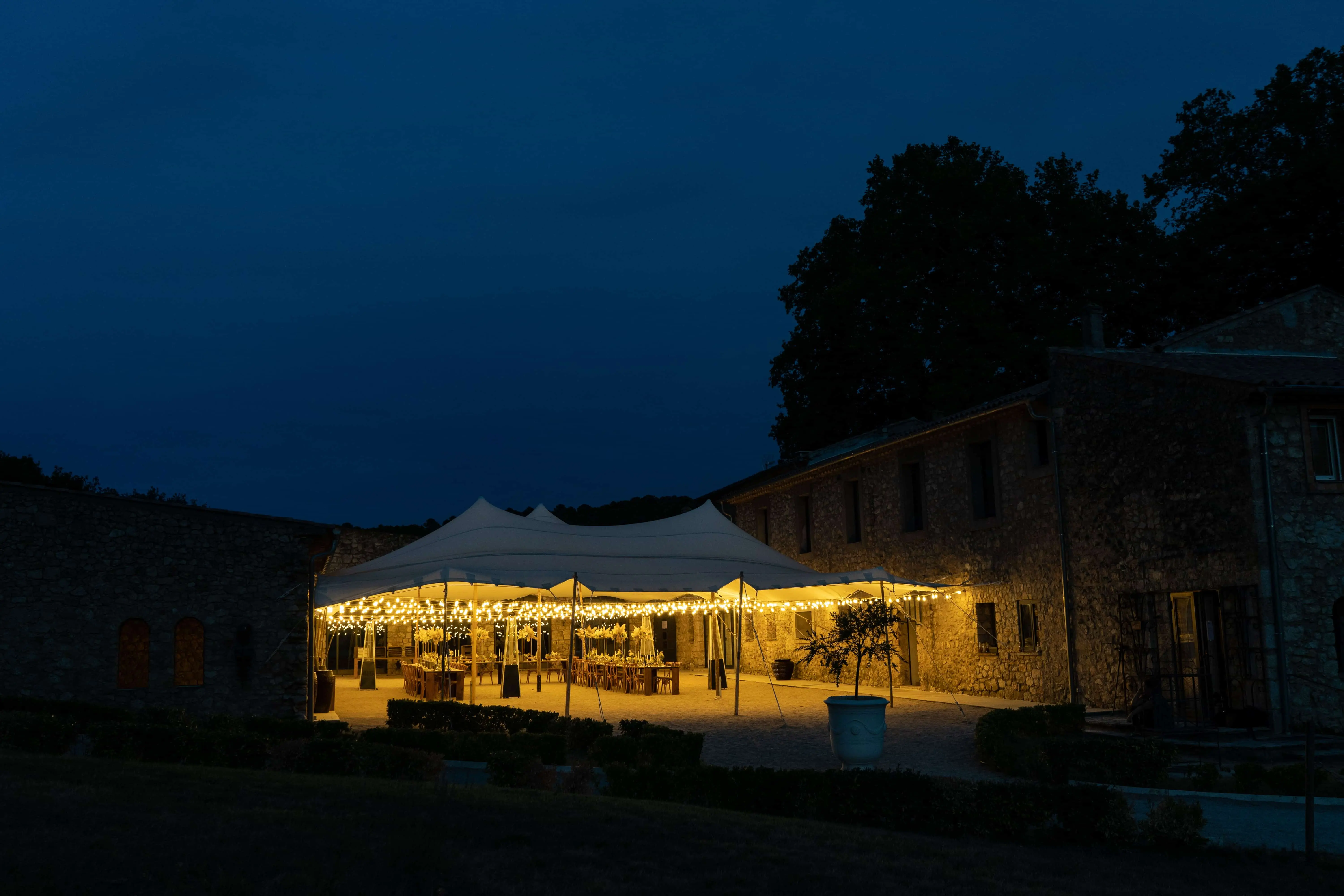 La tente de réception illuminée dans la nuit provençale, devant la bastide